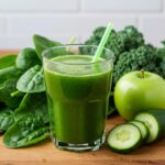 Glas mit frischem grünem Saft aus Spinat, Grünkohl, Gurke und grünen Äpfeln auf Holz