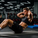 Fit mesomorph individual performing abdominal exercises in a gym, showcasing muscular build and focus